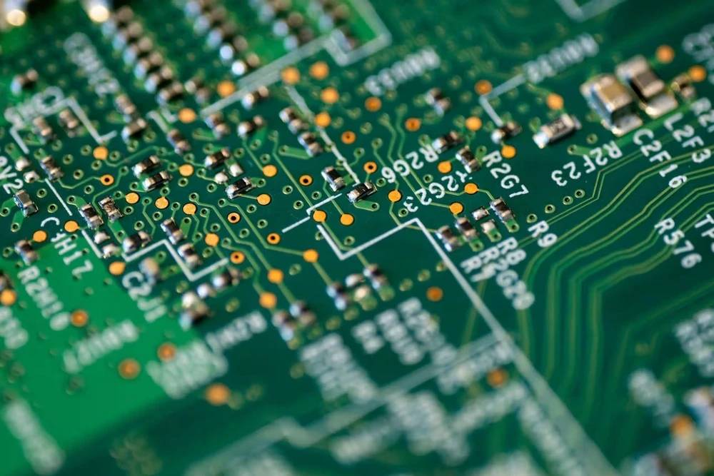 Una placa de circuito impreso (PCB) en primer plano, con trazas metálicas y componentes electrónicos. Simboliza la base de la electrónica moderna, microchips y hardware para dispositivos tecnológicos.