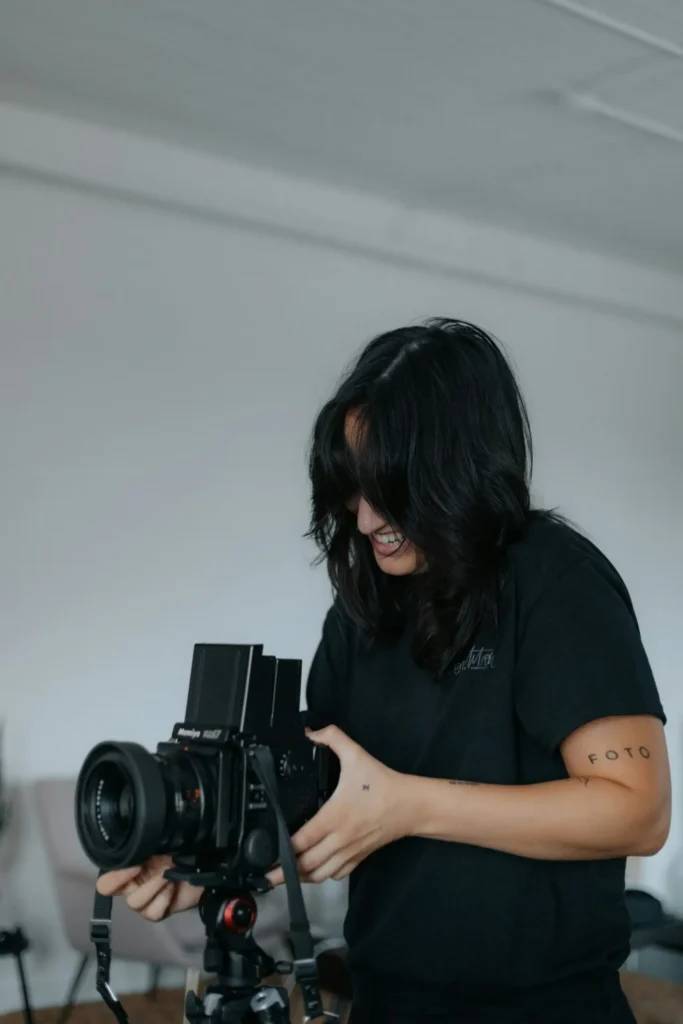 mujer sonriendo mientras toma una foto con una cámara profesional