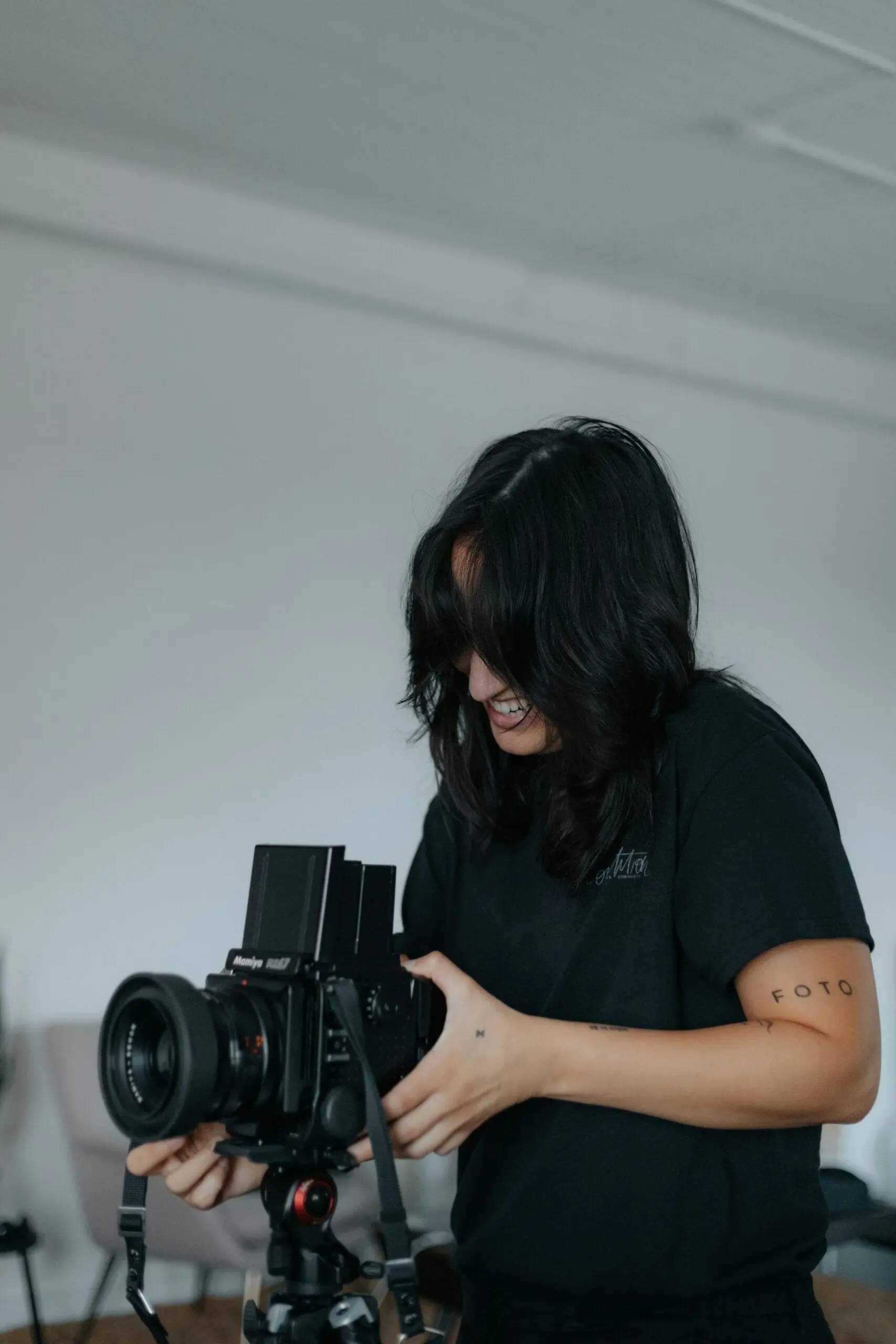 mujer sonriendo mientras toma una foto con una cámara profesional