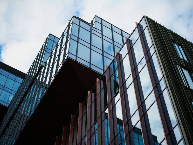 Edificios modernos de oficinas con fachada de vidrio y acero en ángulo picado, simbolizando la integración de la IA en el entorno corporativo.