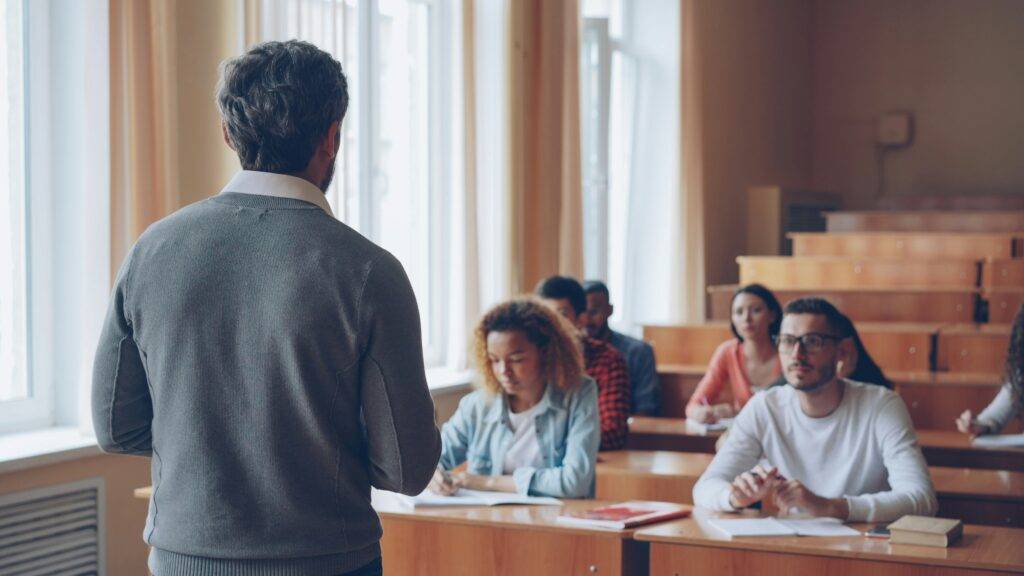 Cómo la tecnología educativa con IA optimiza los procesos y la experiencia de usuario 2 Docente guiando a sus estudiantes en un aula moderna que integra tecnología educativa para mejorar la experiencia de aprendizaje.