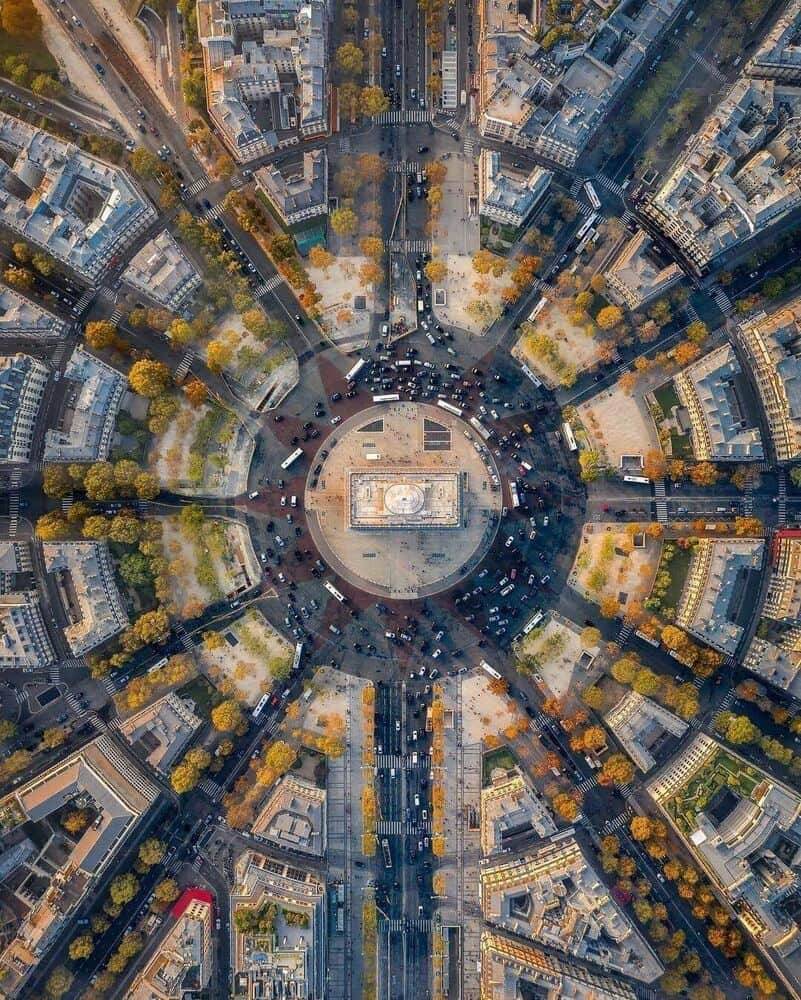 La vista aérea muestra una intersección urbana perfectamente estructurada, símbolo de cómo los distintos flujos de información, de tráfico o de código convergen hacia un nodo común. Representa visualmente la orquestación de modelos de IA en un sistema de desarrollo distribuido