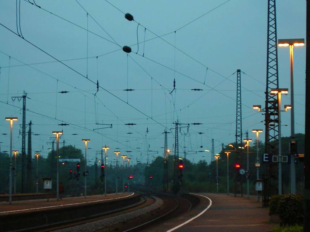 Estación de tren al anochecer con múltiples cables y señales que representan una red compleja.