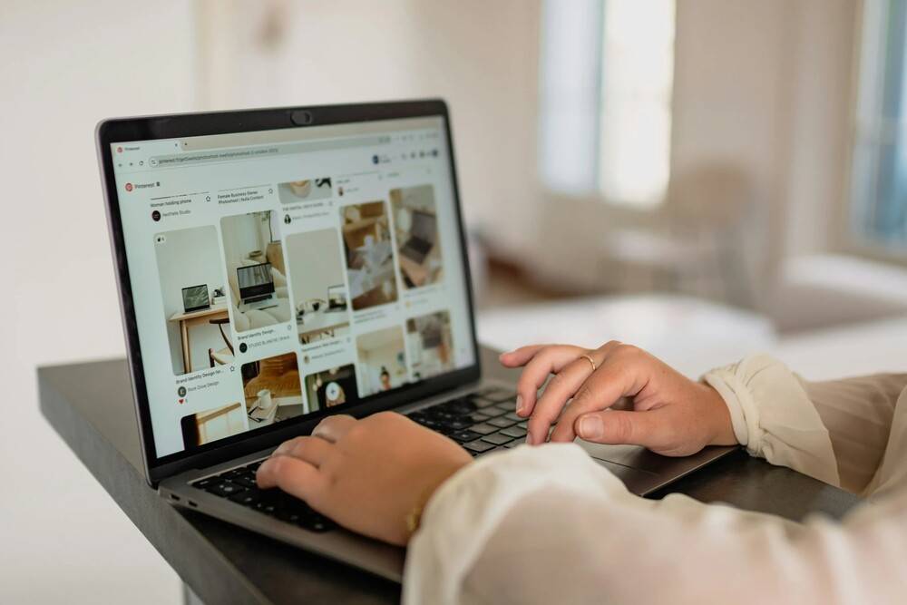 Persona usando un portátil para gestionar un ecommerce, con varias imágenes de productos en pantalla, representando una experiencia digital colaborativa impulsada por IA.