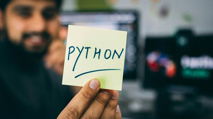 Desarrollador sosteniendo una tarjeta con la palabra Python como metáfora de la reflexión sobre el uso de IA para programar Python en la arquitectura empresarial